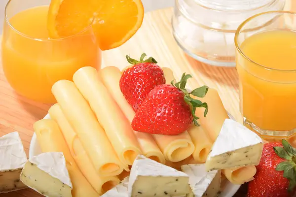 Bir gla portakal suyu ile sarı bir peynir üzerinde sulu çilek