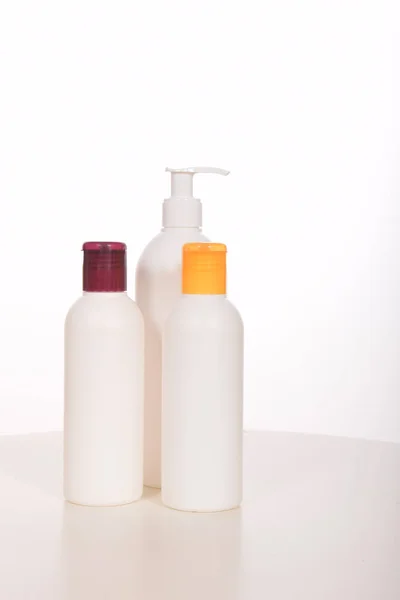 Cosméticos em garrafas de recipientes e tubos de plástico — Fotografia de Stock
