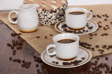 bardak kahve ve süt ve kavrulmuş kahve çekirdekleri ve kek