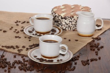 bardak kahve ve süt ve kavrulmuş kahve çekirdekleri ve kek