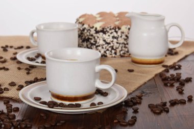 bardak kahve ve süt ve kavrulmuş kahve çekirdekleri ve kek