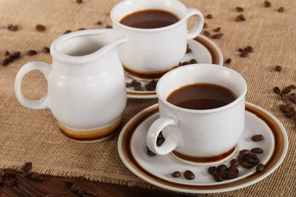 bardak kahve ve süt ve kavrulmuş kahve çekirdekleri