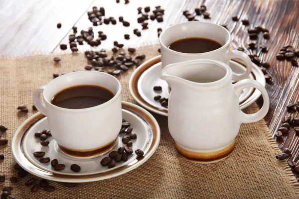 bardak kahve ve süt ve kavrulmuş kahve çekirdekleri