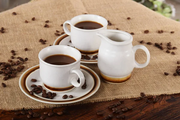 bardak kahve ve süt ve kavrulmuş kahve çekirdekleri