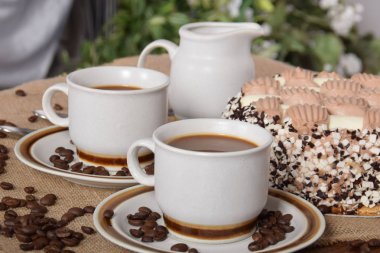 bardak kahve ve süt ve kavrulmuş kahve çekirdekleri