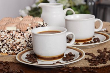 bardak kahve ve süt ve kavrulmuş kahve çekirdekleri