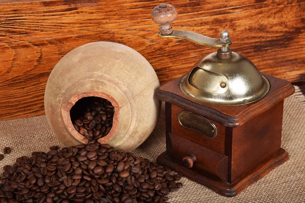 Moedor de café velho e jarro de barro e grãos de café — Fotografia de Stock