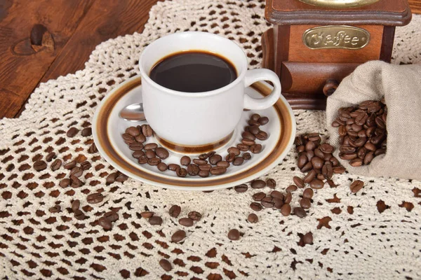 Granos de café recién molido en una bolsa junto a una taza de bl caliente — Foto de Stock