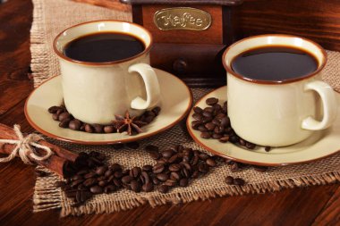 kahve çekirdekleri bir kahve değirmeni ve iki bardak yanındaki gri bir çanta içinde