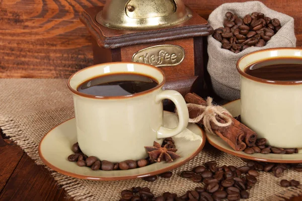 Ziarna kawy w szary worek obok młynek do kawy i dwa Puchary — Zdjęcie stockowe