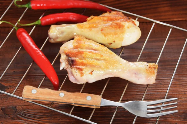 spicy chicken drumsticks on the grill with spicy red chili peppe