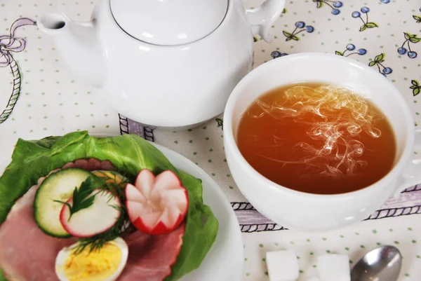 marul jambon, yumurta ve turp ile bir sandviç ile sıcak tatlı çay, 