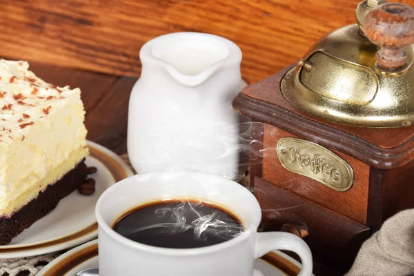 old coffee grinder, cake with cream and coffee in a beige cup wi