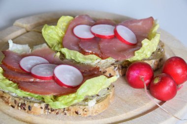 turp dilimleri ile bir marul yaprağı üzerinde füme jambon ile sandviç