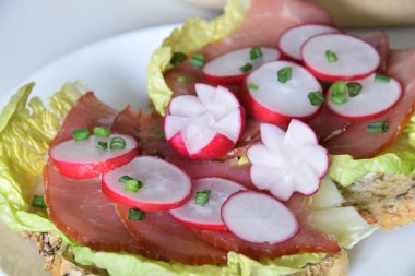 turp dilimleri ile bir marul yaprağı üzerinde füme jambon ile sandviç