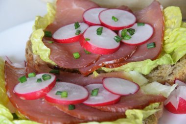 turp dilimleri ile bir marul yaprağı üzerinde füme jambon ile sandviç