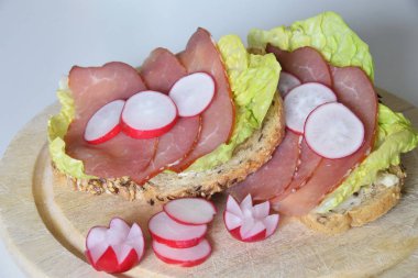 turp dilimleri ile bir marul yaprağı üzerinde füme jambon ile sandviç