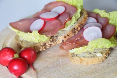 turp dilimleri ile bir marul yaprağı üzerinde füme jambon ile sandviç