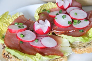 turp dilimleri ile bir marul yaprağı üzerinde füme jambon ile sandviç