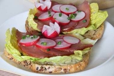 turp dilimleri ile bir marul yaprağı üzerinde füme jambon ile sandviç