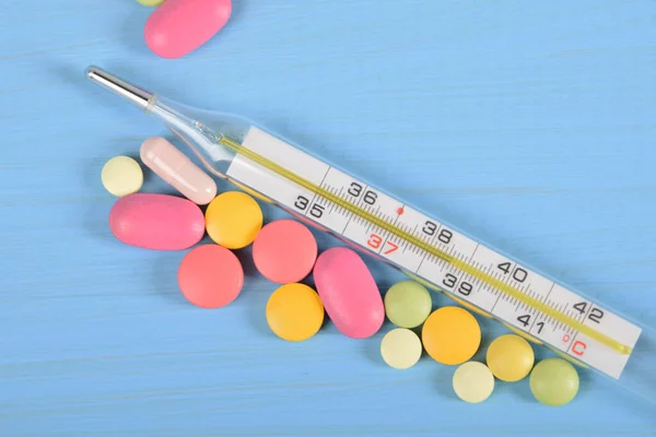scattered colored tablets and a mercury thermometer with free space for text