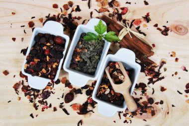 Beyaz seramik kaplarda kurutulmuş çay şeklinde çeşitli meyve ve yapraklar.