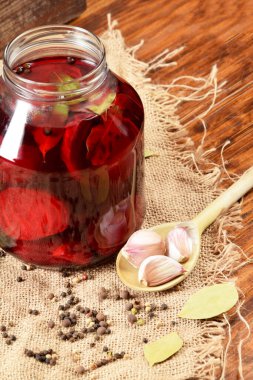 Sarımsak ve pancar parçaları sıcak su ve baharatlarla dolu büyük cam bir kavanozda.