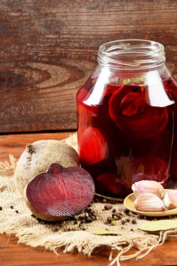 Kavanozun yanında pancar, sarımsak ve baharat parçaları var.