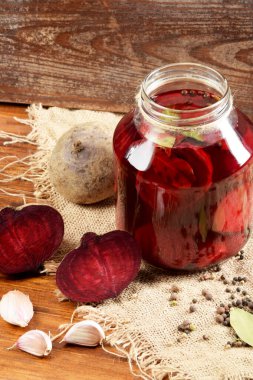 Kavanozun yanında pancar, sarımsak ve baharat parçaları var.