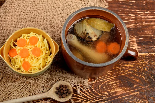 Een Kleipot Vol Kippenbouillon Naast Een Kom Gekookte Pasta — Stockfoto