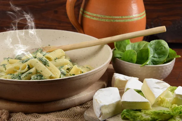 Tahta mutfak tahtasındaki tavada ıspanak soslu makarna.