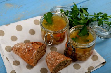 Cam kavanozlarda işkembe çorbası ve ekmeğin yanında taze yeşil maydanoz.