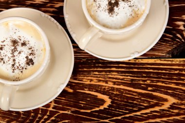 Kahve fincanları ve koyu çikolata serpiştirilmiş süt köpüğü.