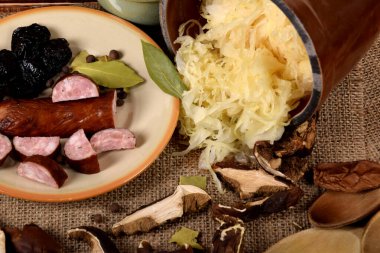 Lahana turşusu kuru erik ve füme sosisin yanındaki kilden dökülür.