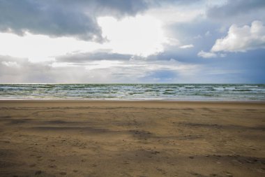 Baltık kıyılarında boş plaj, dalgalar ve dramatik gökyüzü