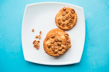 Lezzetli yuvarlak kurabiyeler, beyaz tabakta fındıklar, üst manzara, minimal