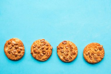 Tasty round cookies with nuts on blue background, top view, copy space, minimal