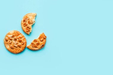 Tasty round cookies with nuts on blue background, top view, copy space