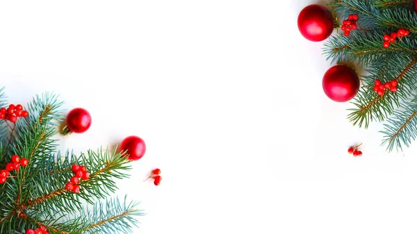 Beyaz arka planda kırmızı takılar olan doğal ladin dalları. Düz konum, üst görünüm, kopyalama alanı. Güzel Noel tebrik kartı