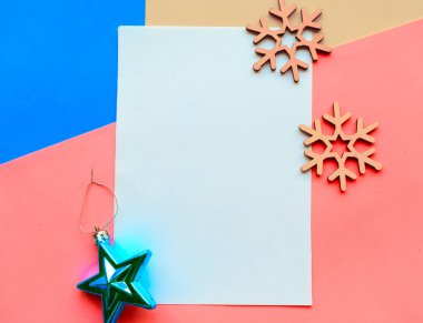 Mavi ve pembe arka planda kar taneleri ve süslemeleri olan Noel tebrik kartı.