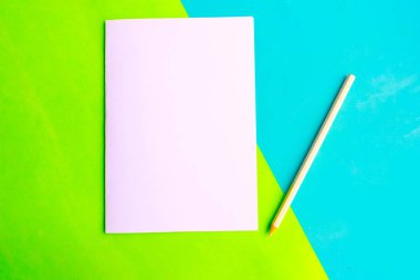 Geometrik yeşil ve mavi kağıdın arka planında beyaz, boş ve kurşun kalem. Düz konum, üst görünüm, en az