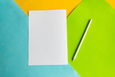 Geometrik mavi, yeşil ve sarı arkaplan üzerinde beyaz model boş ve kalem