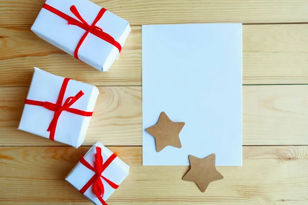 Gift boxes and white mockup blank on wooden background. Merry Christmas and Happy New Year