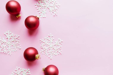 Kırmızı Noel topları pembe arka planda. Düz konum, üst görünüm, kopyalama alanı
