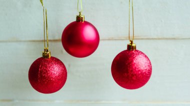 Beyaz ahşap arka planda üç kırmızı takı, yakın plan. Mutlu Noeller ve mutlu yıllar.