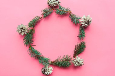 Pembe arka planda ladin dalları ve çam kozalakları Noel çelengi. Düz konum, üst görünüm, kopyalama alanı