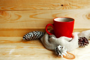 Kırmızı kahve fincanı ve tahta arka planda beyaz kazak. Sıcak kış hala hayat kavramı