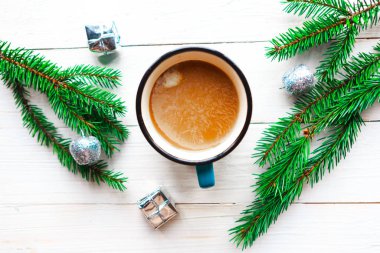 Kahve fincanı, ladin dalları ve beyaz ahşap arka planda Noel süslemeleri olan düz bir fotoğraf. Güzel Xmas tebrik kartı
