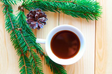 Kahve fincanı, ladin dalları ve beyaz ahşap arka planda Noel süslemeleri olan düz bir fotoğraf. Güzel Xmas tebrik kartı