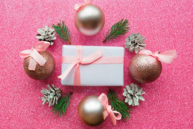 Hediye kutusu ve pembe parıltılı arka planda Noel topları. Düz yerde, üst tarafta. Xmas tebrik kartı, afiş